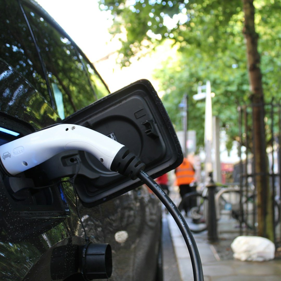 Ladekabel eines Elektroautos, angeschlossen an eine Ladestation in urbaner Umgebung.